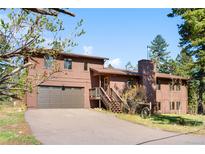 Two-story home features an attached garage, wood siding, and a driveway at 25531 Mosier Cir, Conifer, CO 80433