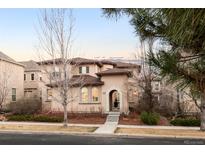 Elegant stucco house with a rounded entryway, a brown roof, and neatly trimmed landscaping at 9122 E 34Th Ave, Denver, CO 80238