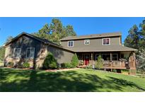 Charming two-story home featuring a welcoming front porch, lush lawn, and mature trees, creating a serene curb appeal at 35550 Running Brook Ln, Elizabeth, CO 80107