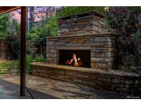 A stone fireplace in the backyard creates a cozy outdoor living space with lush landscaping at 732 Poplar St, Denver, CO 80220