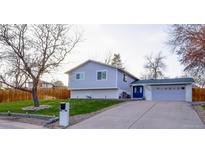 Charming bi-level home with attached garage, blue door, and well-maintained front yard at 5389 W Roxbury Pl, Littleton, CO 80128