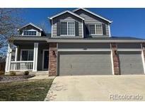 Inviting two-story home featuring gray siding, brick accents, a well-maintained lawn, and a spacious three-car garage at 1169 N Tabor Dr, Castle Rock, CO 80104
