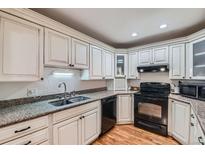 White kitchen cabinets, granite countertops, and black appliances at 246 S 22Nd Ave, Brighton, CO 80601