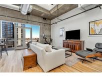 Bright living room features hardwood floors, exposed ductwork, and a large window with city views at 2020 Arapahoe St # 1250, Denver, CO 80205
