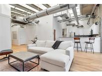 Bright, open living space with white sofa, hardwood floors, and modern industrial design at 2020 Arapahoe St # 1250, Denver, CO 80205