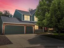 Charming two-story home features a three-car garage and a welcoming front porch at dusk at 8953 W Brandt Pl, Littleton, CO 80123