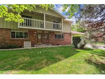 Inviting two-story brick home featuring charming balconies and a lush green lawn at 372 Vance St, Lakewood, CO 80226