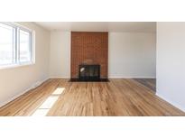 Bright living room with a brick fireplace and hardwood flooring at 785 Planet Pl, Thornton, CO 80260