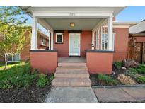 Charming red brick home featuring a covered front porch with an inviting entryway and well-manicured landscaping at 328 S Lincoln St, Denver, CO 80209