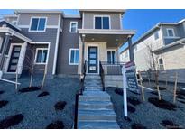 Modern two-story townhome featuring stone accents, a covered entryway, and a professionally landscaped front yard at 22792 E Tufts Ave # A, Aurora, CO 80015