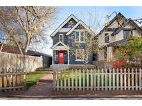 Charming two-story home with a red door, complemented by a brick walkway and white picket fence at 3142 W 26Th Ave, Denver, CO 80211