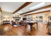 Spacious living room with hardwood floors, stone fireplace, and a pool table, perfect for entertaining guests at 24149 Shooting Star Dr, Golden, CO 80401
