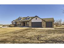 Charming two-story brick home featuring a three-car garage and a well-manicured front yard at 16650 Shadow Wood Ct, Hudson, CO 80642