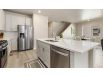 Modern kitchen featuring a stainless steel refrigerator and an island with a sink at 6150 Sugarloaf St, Brighton, CO 80601