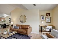 Comfortable living room with a supple brown leather sofa, desk, and a round mirror on a modern wall at 12281 E Tennessee Dr # 302, Aurora, CO 80012