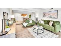 A bright living room with hardwood floors, green sofas, a round table, and a desert-themed painting at 8060 E Girard Ave # 311, Denver, CO 80231