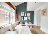 Bright living room featuring a modern sofa, large windows, and stylish decor against an accent wall at 3249 W Fairview Pl # 207, Denver, CO 80211