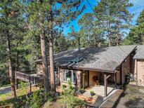 Charming home exterior featuring a spacious deck and a welcoming front porch with mature trees at 28251 Shadow Mountain Dr, Conifer, CO 80433