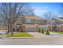 Inviting townhome with a well-manicured lawn, two-car garage, and brick accents on a tree lined street at 1550 S Syracuse St, Denver, CO 80231