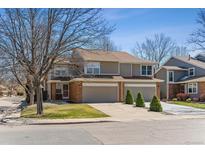 Traditional two-story townhome featuring an attached garage and well-manicured front yard at 1550 S Syracuse St, Denver, CO 80231