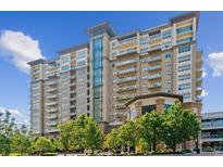 Upscale condo building with brick and tan exterior, plentiful windows, and attractive landscaping on a sunny day at 5455 Landmark Pl # 1414, Greenwood Village, CO 80111