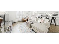 Inviting living room with a comfortable gray sectional couch and view to the kitchen bar seating at 677 Vrain St # 15, Denver, CO 80204