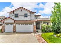 Two-story home featuring a three-car garage, brick accents, well manicured lawn, and classic architectural details at 10683 Amesbury Way, Highlands Ranch, CO 80126
