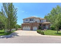 Charming two-story home featuring a brick facade, three-car garage, and lush landscaping at 7858 Oban Ct, Lone Tree, CO 80124
