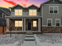 Charming two-story home featuring a welcoming front porch with stone accents and snow covered yard at 255 E 4Th St, Berthoud, CO 80513