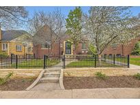 Charming brick home with a manicured front yard, a stone wall, and a wrought iron fence showcasing curb appeal at 944 S Euclid Way, Denver, CO 80209