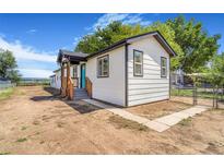 Charming home featuring white siding, black trim, and a welcoming blue front door at 1219 Lilac Dr, Lochbuie, CO 80603