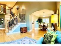 Open-concept living room featuring staircase, light hardwood floors, and dining area at 6002 Alkire Ct, Arvada, CO 80004