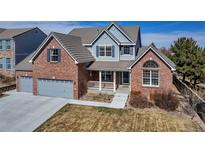 Charming two-story home with brick facade, blue accents, and well-manicured front yard at 23525 Painted Hills St, Parker, CO 80138