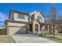 Two story home with tan siding, brick porch detail, large garage and manicured lawn at 5177 Delphinium Cir, Brighton, CO 80601