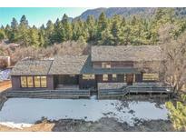 Front elevation of a two-story house showcasing a wood and stone facade with a deck overlooking the mountain view at 778 Suncrest Rd, Palmer Lake, CO 80133