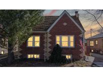 Charming brick two-story home featuring an American flag and beautifully landscaped front yard at 1560 Hudson St, Denver, CO 80220