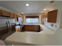 Well-lit kitchen with stainless steel appliances and a breakfast bar that opens to the living area at 10129 Grove Ct # B, Westminster, CO 80031
