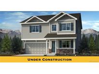 Charming two-story home with gray siding, stone accents, and a two-car garage, all set against a backdrop of mountains at 716 N Carrie Ct, Watkins, CO 80137