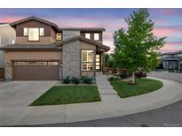 Beautiful two-story home featuring a two-car garage, stone accents and manicured lawn with mature trees at 14384 Big Stone Dr, Parker, CO 80134
