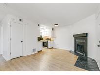 Bright living room with wood flooring, a door, and a corner fireplace with black tile surround at 1820 Newland Ct # 313, Lakewood, CO 80214