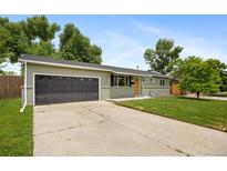 Charming single-story home featuring a well-maintained lawn, a dark gray garage door, and fresh light-green paint at 1205 W 101St Ave, Northglenn, CO 80260