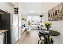 Bright living room with large windows, light wood floors, and an adjacent modern kitchen at 5375 W 14Th Ave, Lakewood, CO 80214