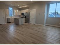 Bright open kitchen with stainless steel appliances and an island with modern pendant lighting at 4737 E Iliff Ave, Denver, CO 80222