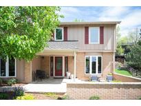 Charming two-story home featuring a brick facade, red shutters, and a welcoming front porch with seating at 7414 S Monroe Ct, Centennial, CO 80122
