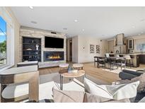 Bright living room with hardwood floors, stone fireplace, built in shelving, and an open floor plan to the kitchen at 3615 Navajo St, Denver, CO 80211