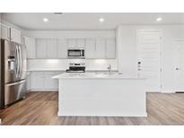 Modern kitchen featuring white cabinets, stainless steel appliances, and a center island with a sink at 487 Interlocken Blvd # 408, Broomfield, CO 80021