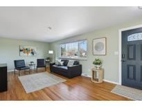 Inviting living room with hardwood floors, black leather sofa, and lots of natural light from large windows at 3406 E Fair Pl, Centennial, CO 80121
