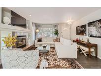 Bright living room featuring a cozy fireplace, white sectional, and stylish rug at 1382 Braewood Ave, Highlands Ranch, CO 80129