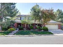 Traditional two-story home with well-maintained lawn and mature trees on a sunny day at 10886 E Berry Ave, Englewood, CO 80111
