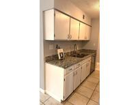 Classic kitchen featuring granite countertops, stainless sink, and white cabinets at 7495 E Quincy Ave # 205, Denver, CO 80237